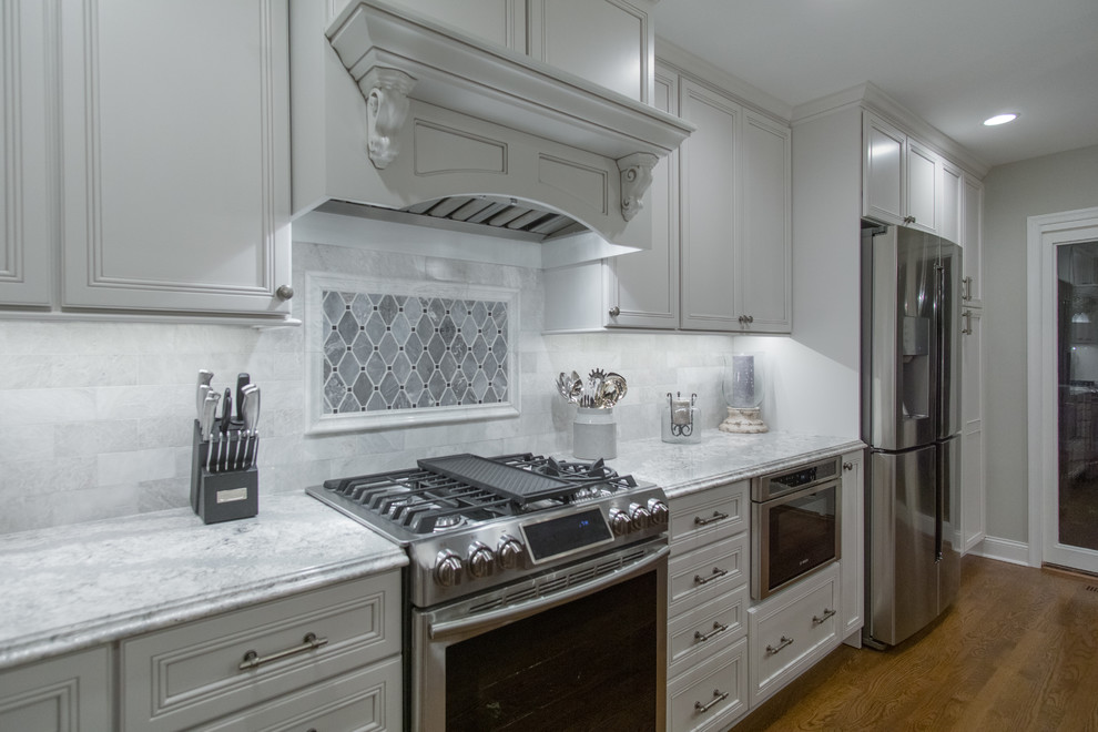 Inspiration for a large transitional single-wall eat-in kitchen in Philadelphia with a drop-in sink, flat-panel cabinets, white cabinets, soapstone benchtops, white splashback, stone tile splashback, stainless steel appliances, medium hardwood floors, with island and brown floor.
