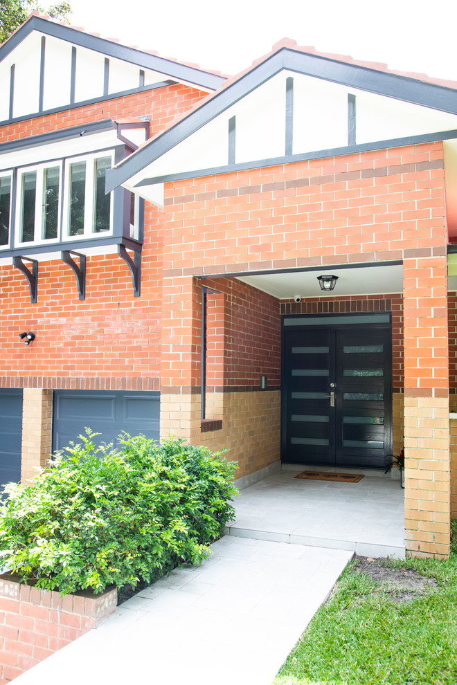 This is an example of an expansive transitional two-storey brick red house exterior in Sydney with a gable roof and a tile roof.