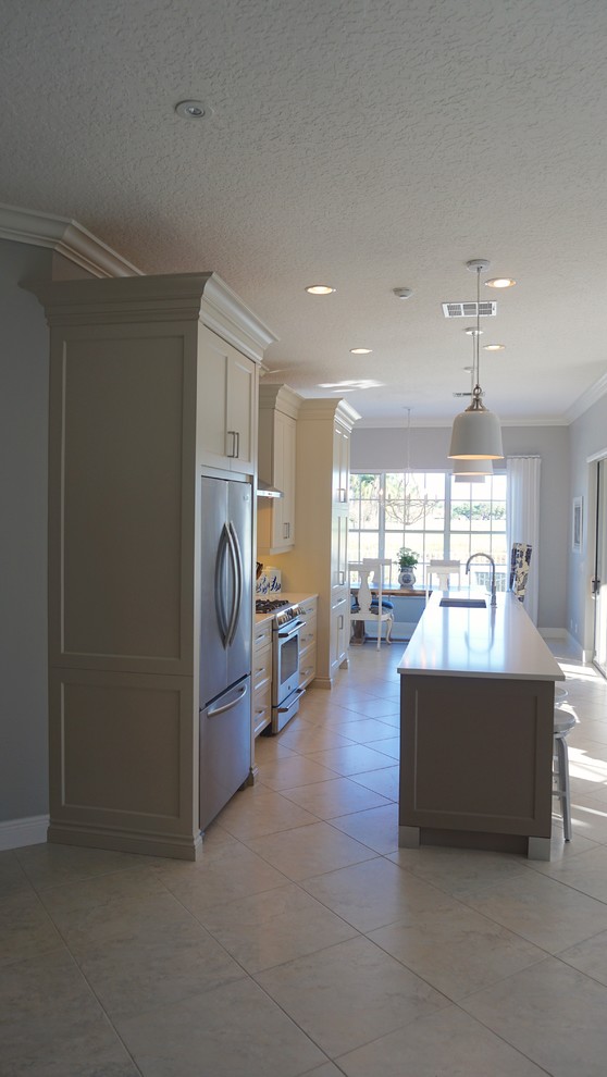 Mid-sized transitional l-shaped ceramic tile and beige floor open concept kitchen photo in Miami with an undermount sink, recessed-panel cabinets, beige cabinets, solid surface countertops, beige backsplash, mosaic tile backsplash, stainless steel appliances and an island