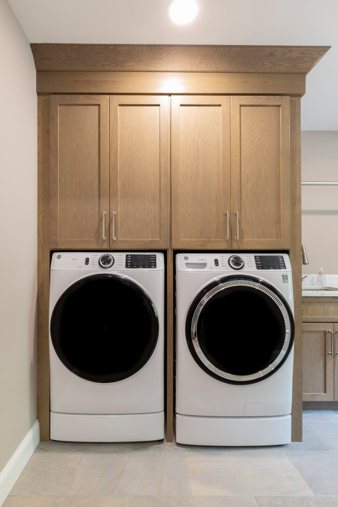 Medium sized traditional single-wall laundry cupboard in New York with a submerged sink, shaker cabinets, light wood cabinets, engineered stone countertops, engineered quartz splashback, beige walls, porcelain flooring, a side by side washer and dryer, grey floors and white worktops.