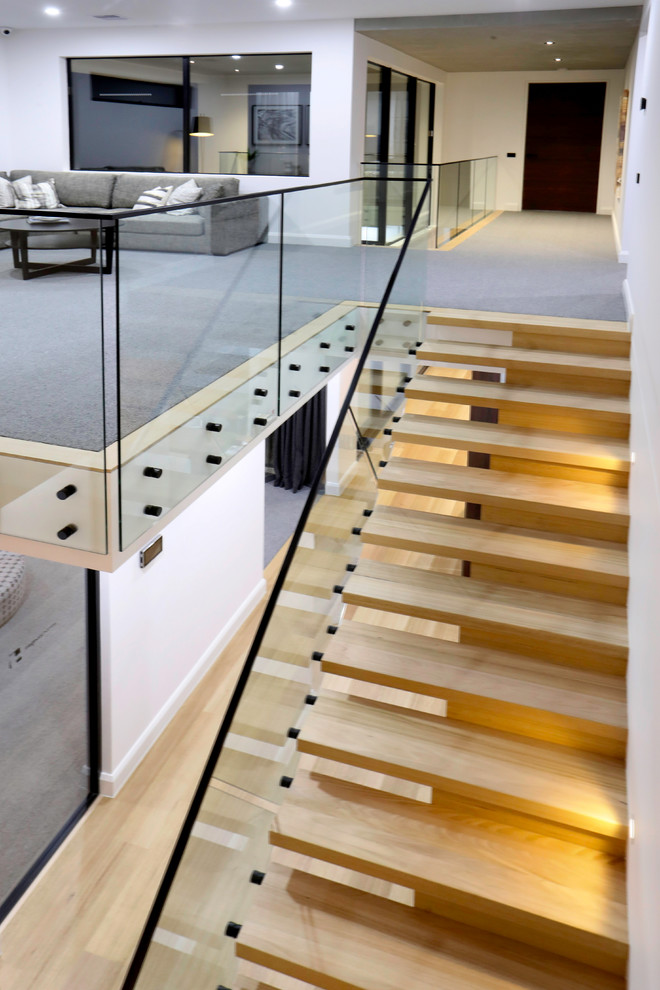 Design ideas for a large industrial wood straight staircase in Melbourne with wood risers and glass railing.