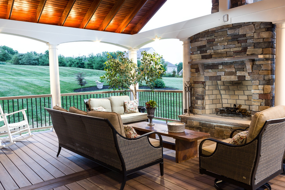 Example of a large transitional backyard deck design in Baltimore with a fire pit and a roof extension