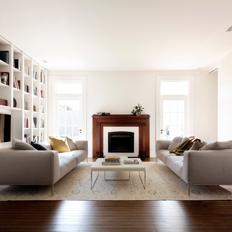 Photo of a transitional formal enclosed living room in Sydney with white walls, medium hardwood floors and a standard fireplace.