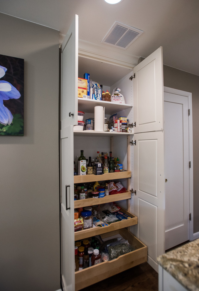 Inspiration for a large transitional u-shaped medium tone wood floor and brown floor eat-in kitchen remodel with an undermount sink, shaker cabinets, white cabinets, granite countertops, beige backsplash, travertine backsplash, paneled appliances and an island
