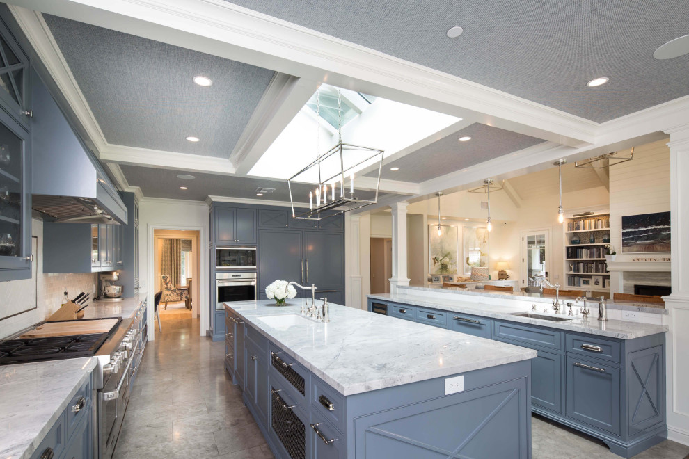 Photo of an expansive transitional l-shaped eat-in kitchen in Los Angeles with an undermount sink, shaker cabinets, blue cabinets, quartzite benchtops, white splashback, ceramic splashback, panelled appliances, limestone floors, multiple islands, grey floor and white benchtop.