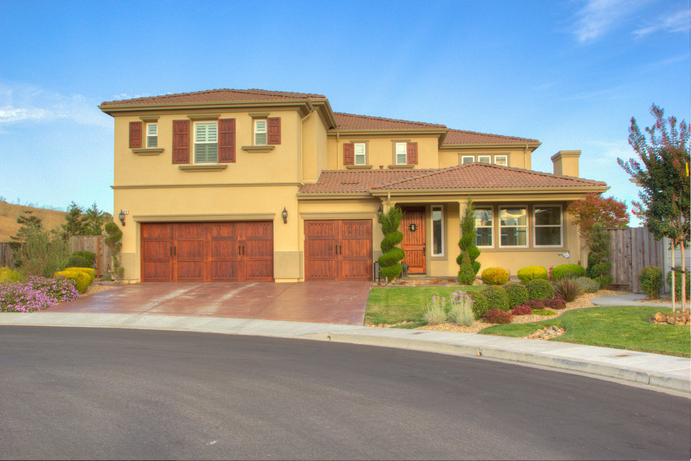 Photo of a large country two-storey stucco yellow exterior in Sacramento with a hip roof.