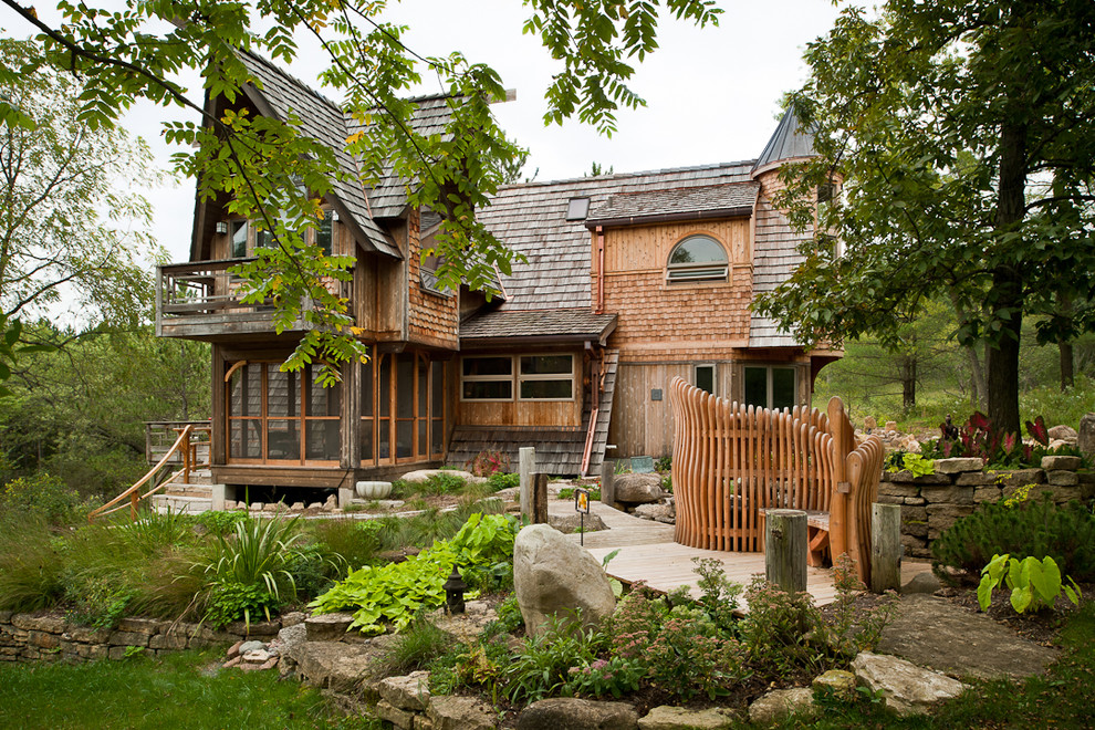 Large eclectic two-storey brown house exterior in Other with wood siding, a gable roof, a shingle roof and a brown roof.