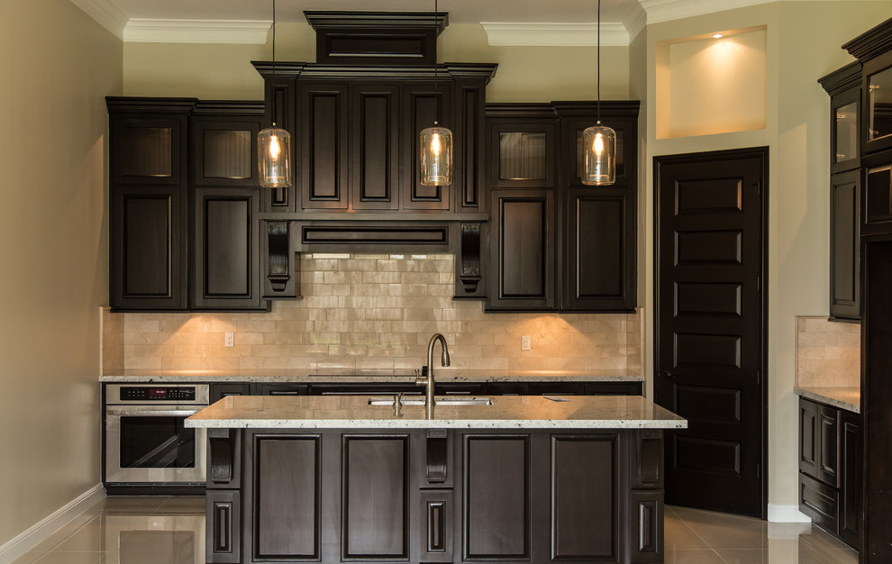 Transitional porcelain tile kitchen photo in Austin with an undermount sink, raised-panel cabinets, dark wood cabinets, granite countertops, beige backsplash, subway tile backsplash, stainless steel appliances and an island