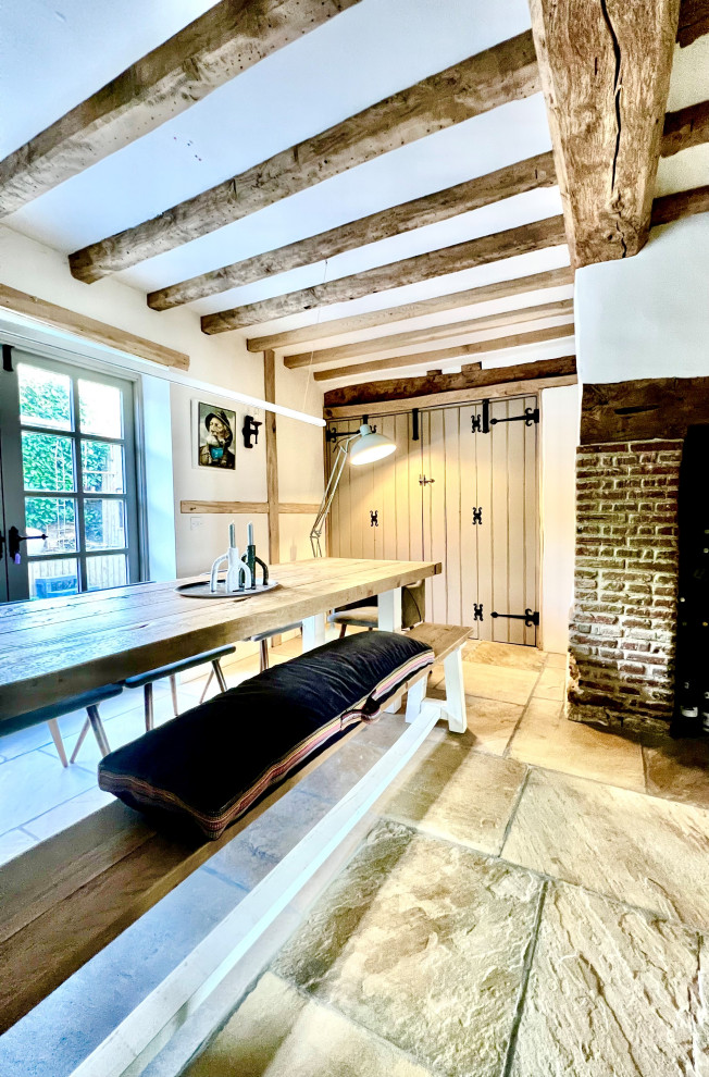 Mittelgroßes Uriges Esszimmer mit beiger Wandfarbe, Kalkstein, Eckkamin, Kaminumrandung aus Backstein, grauem Boden, freigelegten Dachbalken und Ziegelwänden in Oxfordshire