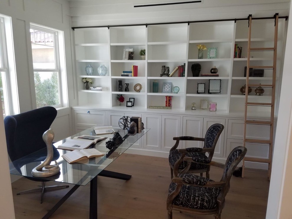 This is an example of a mid-sized country study room in Los Angeles with white walls, light hardwood floors, no fireplace, a freestanding desk and beige floor.