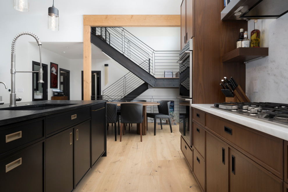 Inspiration for a mid-sized industrial l-shaped open plan kitchen in Denver with shaker cabinets, medium wood cabinets, marble benchtops, panelled appliances, light hardwood floors, with island, brown floor and multi-coloured benchtop.