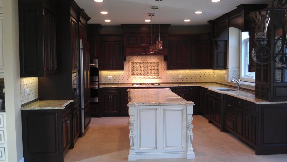 This is an example of a large traditional u-shaped eat-in kitchen in Chicago with a single-bowl sink, raised-panel cabinets, dark wood cabinets, granite benchtops, multi-coloured splashback, mosaic tile splashback, stainless steel appliances, travertine floors and with island.