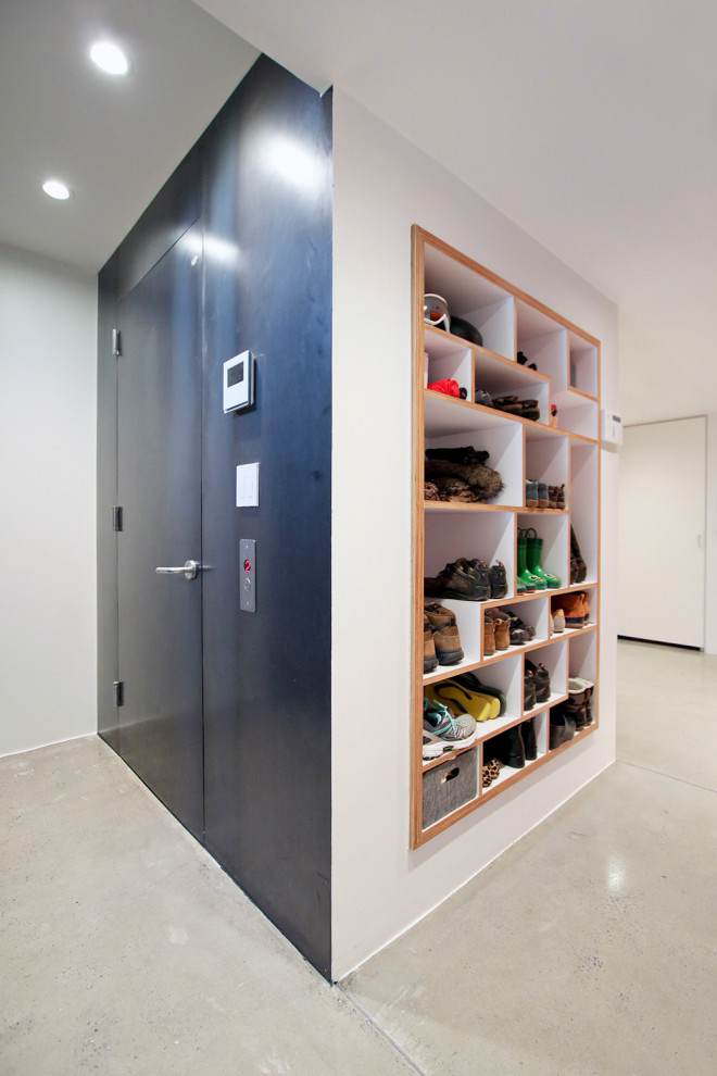 Design ideas for a mid-sized modern mudroom in New York with white walls, concrete floors, a single front door and a white front door.