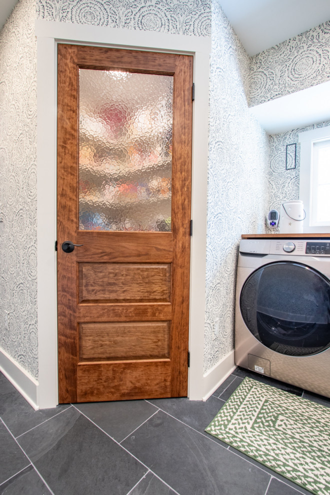 Esempio di una lavanderia con ante in stile shaker, ante bianche, top in legno, pareti blu, pavimento in ardesia, pavimento grigio, top marrone e carta da parati