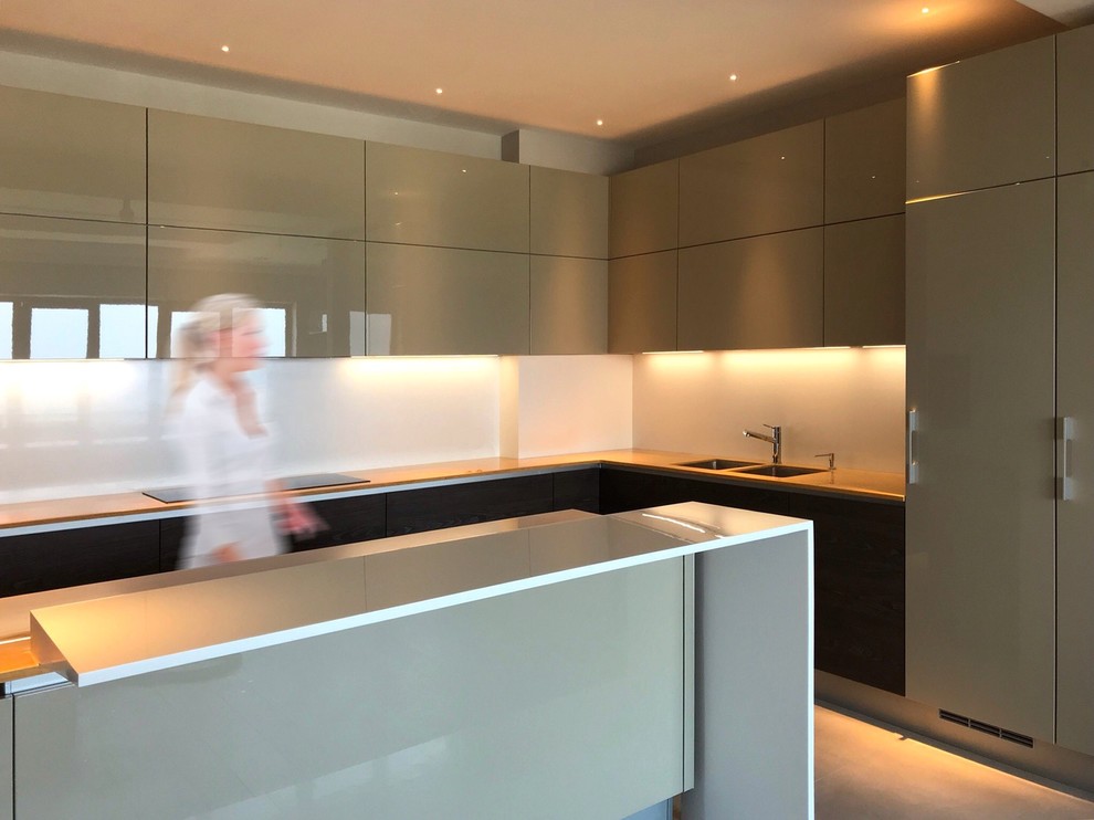 Inspiration for a large modern u-shaped eat-in kitchen in Other with a double-bowl sink, flat-panel cabinets, solid surface benchtops, white splashback, porcelain floors, with island, beige floor, beige cabinets, glass sheet splashback, black appliances and yellow benchtop.
