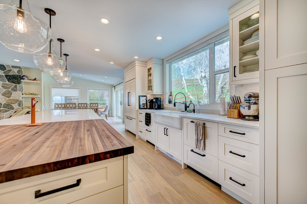 Eat-in kitchen - mid-sized transitional l-shaped medium tone wood floor and beige floor eat-in kitchen idea in Vancouver with an undermount sink, shaker cabinets, white cabinets, quartz countertops, white backsplash, ceramic backsplash, stainless steel appliances and an island