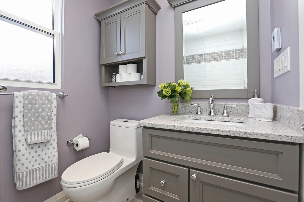 This is an example of a small transitional kids bathroom in Toronto with grey cabinets, an alcove tub, a shower/bathtub combo, a one-piece toilet, white tile, purple walls and an undermount sink.