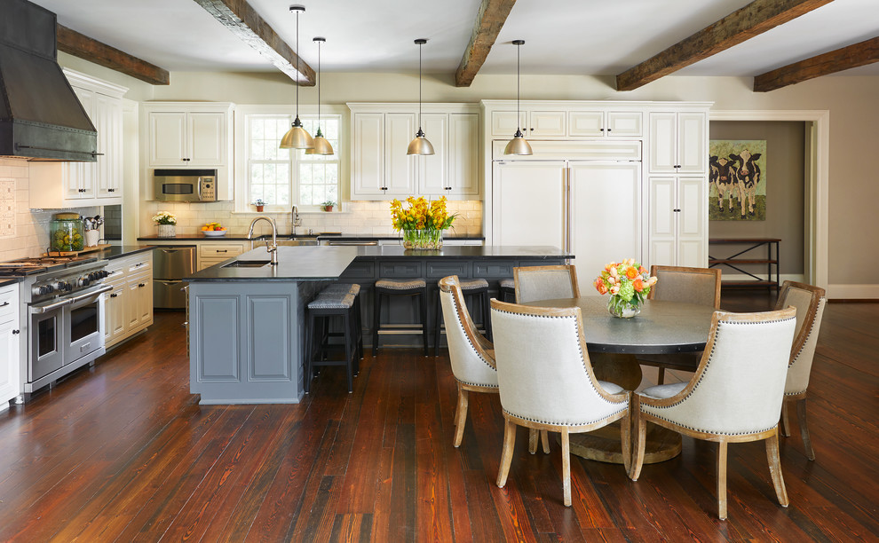 Inspiration for a mid-sized traditional l-shaped open plan kitchen in Nashville with an undermount sink, raised-panel cabinets, white cabinets, white splashback, stainless steel appliances, medium hardwood floors, with island, brown floor and porcelain splashback.