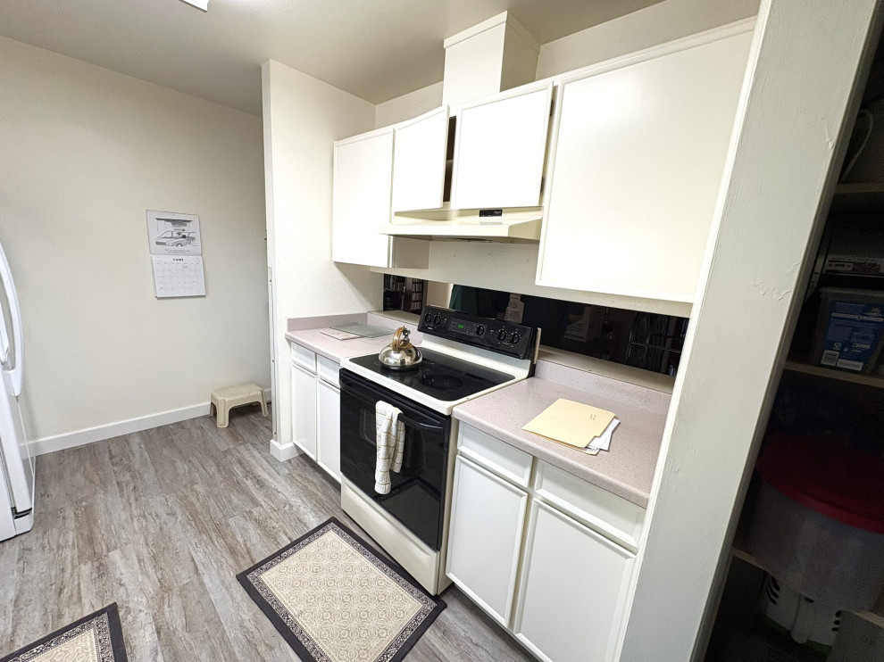 Inspiration for a small transitional vinyl floor and brown floor enclosed kitchen remodel with an undermount sink, shaker cabinets, white cabinets, quartzite countertops, blue backsplash, mosaic tile backsplash, white appliances, an island and white countertops
