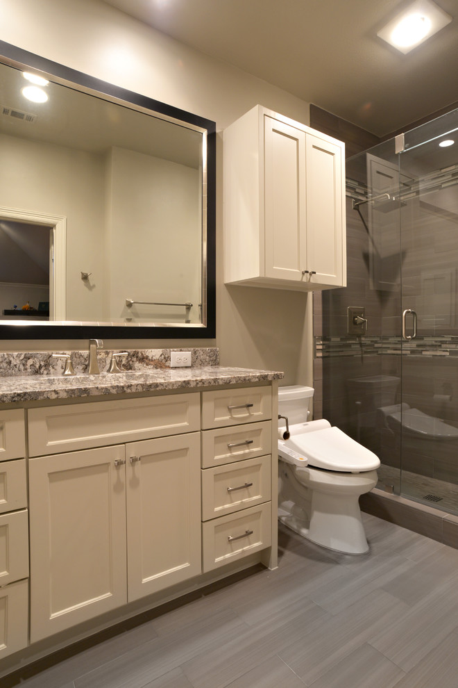 Photo of a mid-sized transitional master bathroom in Dallas with recessed-panel cabinets, beige cabinets, an alcove shower, a two-piece toilet, multi-coloured tile, matchstick tile, beige walls, plywood floors, an undermount sink and granite benchtops.