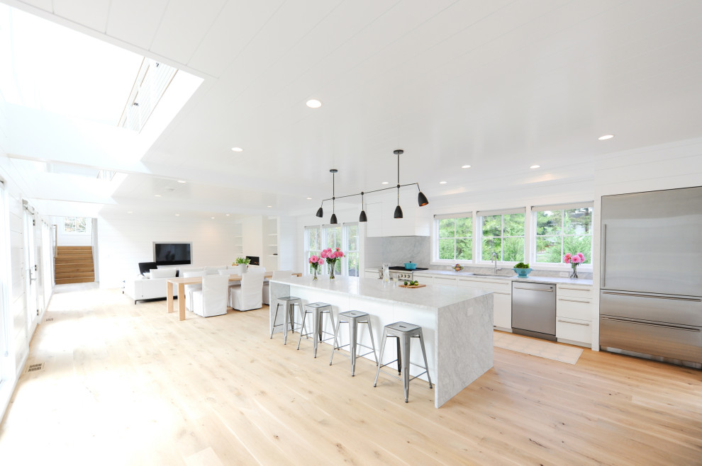Inspiration for a modern open plan kitchen in Boston with a single-bowl sink, flat-panel cabinets, white cabinets, marble benchtops, stainless steel appliances, light hardwood floors, with island, white benchtop and timber.
