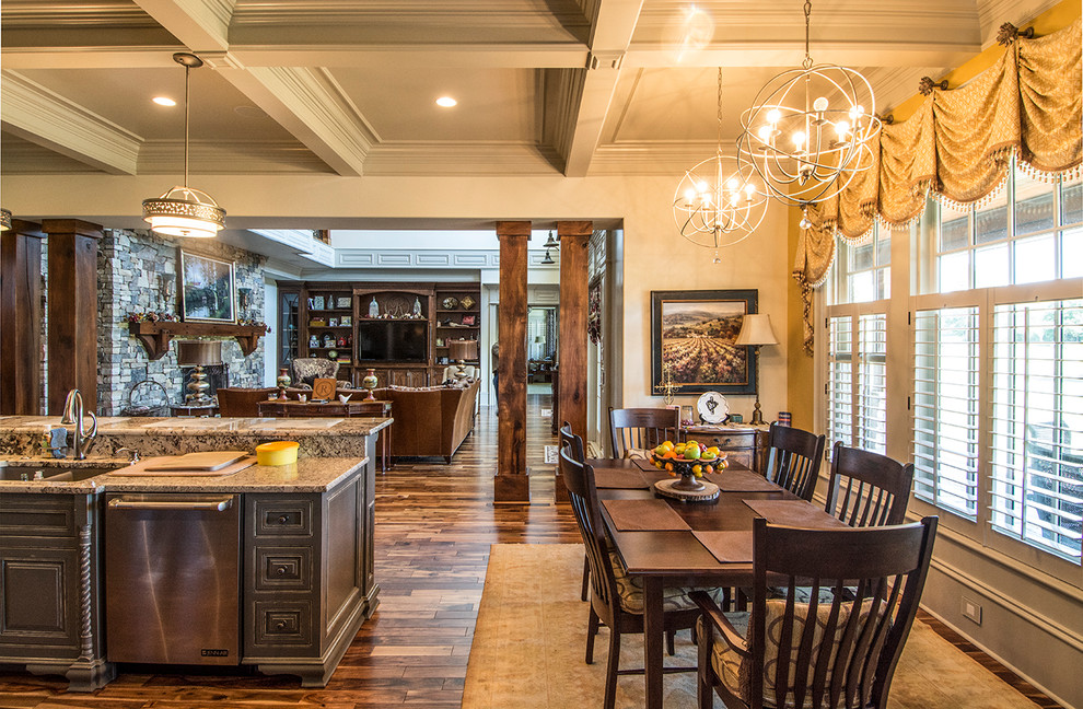 Large mountain style u-shaped medium tone wood floor and brown floor eat-in kitchen photo with an undermount sink, raised-panel cabinets, distressed cabinets, granite countertops, brown backsplash, stone tile backsplash, stainless steel appliances, two islands and multicolored countertops