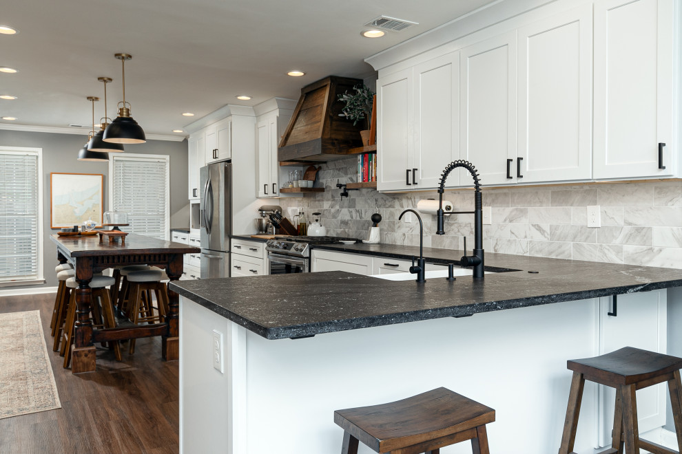 Photo of a country kitchen in Atlanta with a farmhouse sink, shaker cabinets, white cabinets, granite benchtops, ceramic splashback, stainless steel appliances and laminate floors.