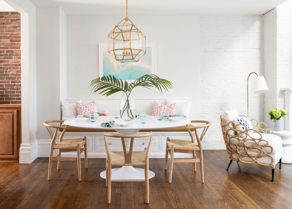 This is an example of a small nautical dining room in Boston with banquette seating, white walls, medium hardwood flooring and brown floors.