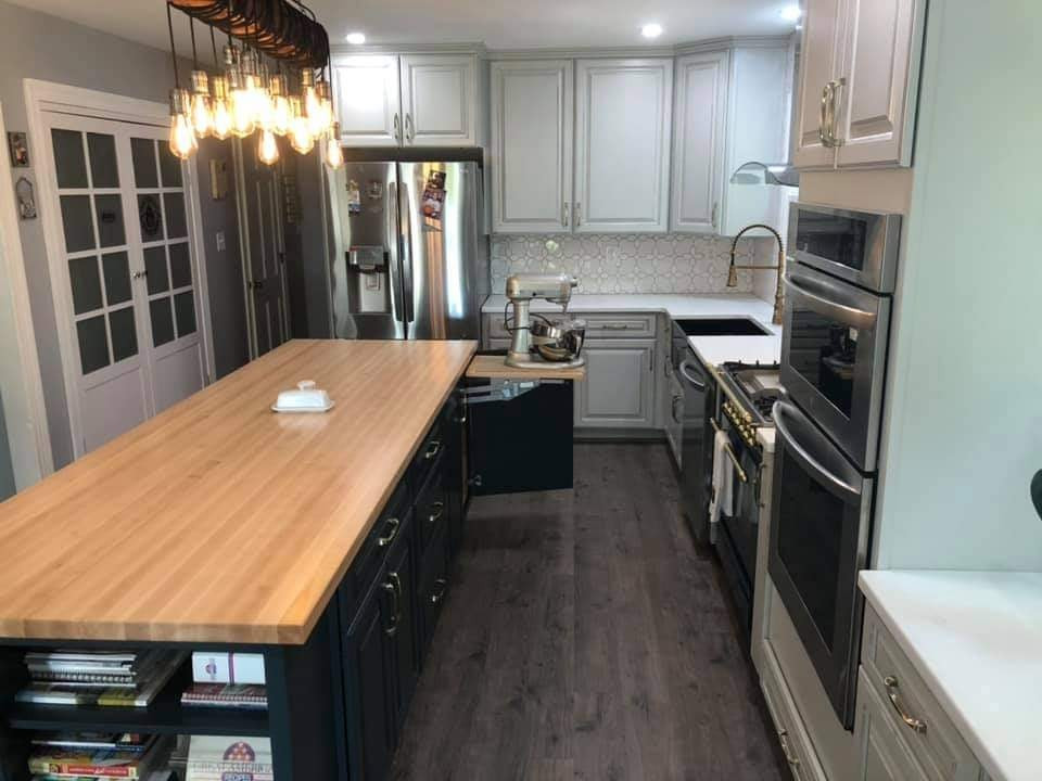Kitchen - mid-sized transitional l-shaped vinyl floor and brown floor kitchen idea in DC Metro with a farmhouse sink, raised-panel cabinets, gray cabinets, solid surface countertops, white backsplash, ceramic backsplash, stainless steel appliances, an island and white countertops