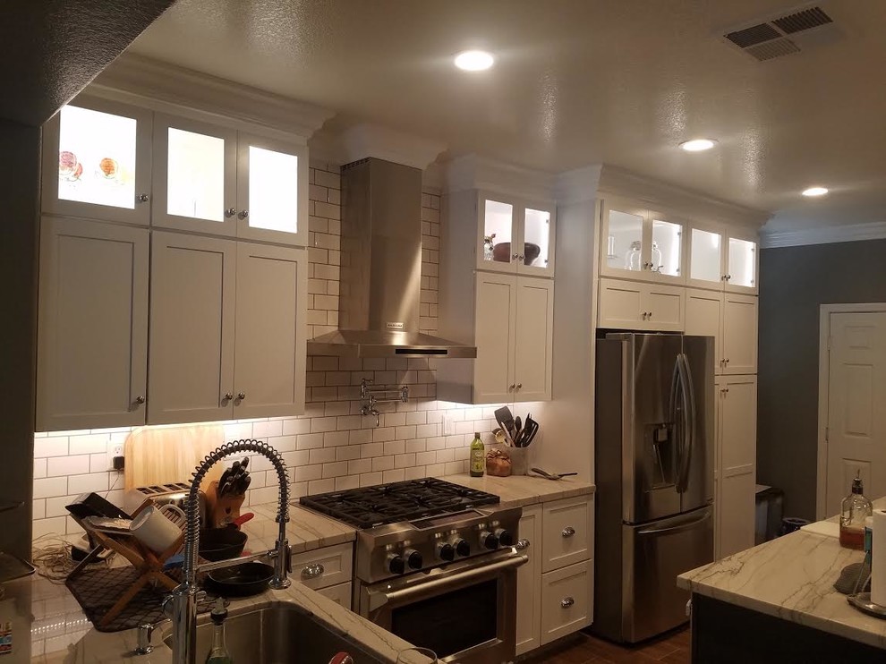 Example of a large transitional u-shaped porcelain tile and brown floor enclosed kitchen design in Los Angeles with shaker cabinets, white cabinets, quartzite countertops, stainless steel appliances, an island, multicolored countertops, an undermount sink, white backsplash and subway tile backsplash