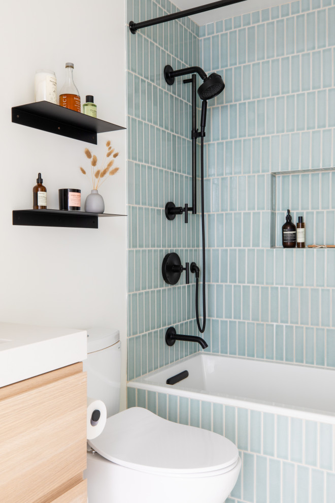 Foto på ett litet nordiskt vit badrum, med släta luckor, skåp i ljust trä, ett badkar i en alkov, en dusch i en alkov, blå kakel, keramikplattor, vita väggar, klinkergolv i keramik, ett undermonterad handfat, bänkskiva i kvarts och svart golv
