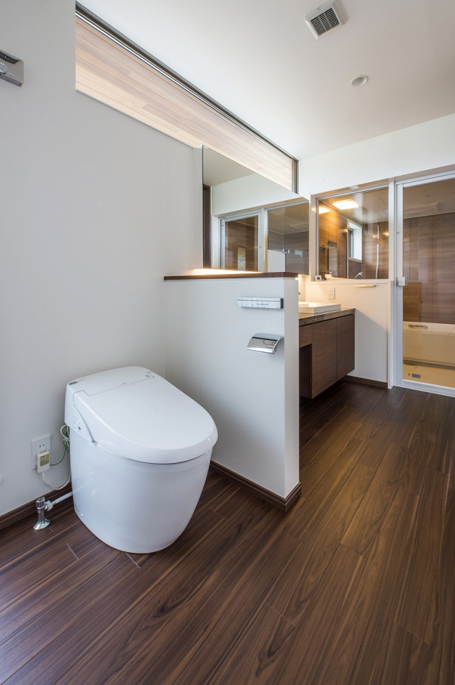 Moderne Gästetoilette mit hellbraunen Holzschränken, weißer Wandfarbe, braunem Holzboden, Marmor-Waschbecken/Waschtisch, braunem Boden und grauer Waschtischplatte in Kobe