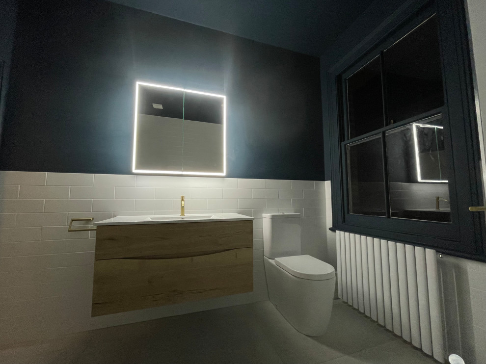 Пример оригинального дизайна: большая детская ванная комната в стиле модернизм с плоскими фасадами, светлыми деревянными фасадами, отдельно стоящей ванной, открытым душем, синими стенами, полом из керамогранита, серым полом, открытым душем, тумбой под одну раковину и подвесной тумбой
