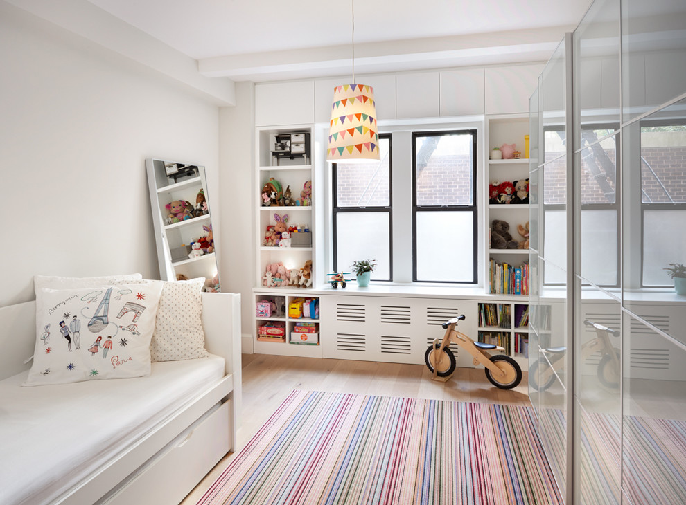 Photo of a contemporary kids' bedroom for kids 4-10 years old in New York with white walls, light hardwood floors and beige floor.