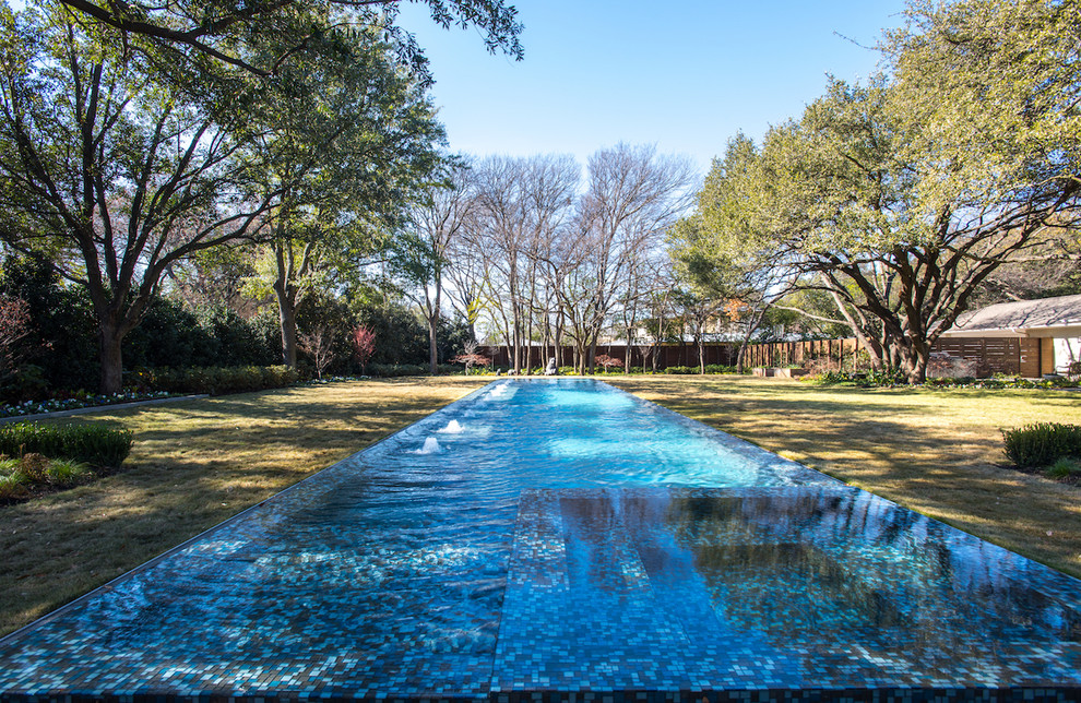 Example of a huge transitional backyard rectangular infinity pool design in Dallas