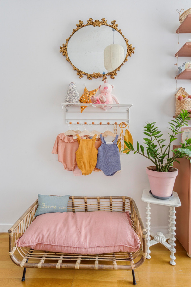 Foto de habitación de bebé niña bohemia de tamaño medio con paredes rosas, boiserie, suelo de madera en tonos medios y suelo marrón