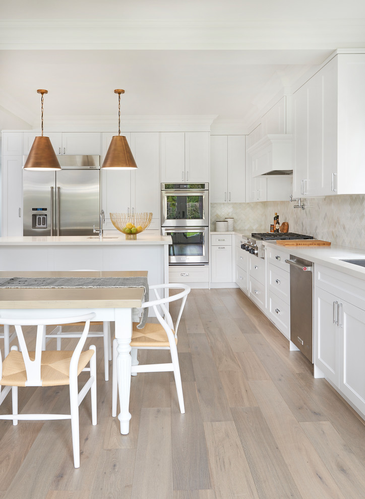 Eat-in kitchen - large transitional light wood floor and beige floor eat-in kitchen idea in Toronto with an undermount sink, shaker cabinets, white cabinets, quartz countertops, white backsplash, stainless steel appliances, an island and white countertops