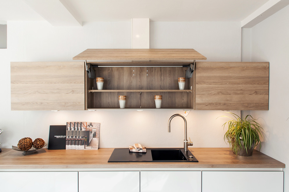 This is an example of a mid-sized scandinavian single-wall kitchen in Dusseldorf with a drop-in sink, light wood cabinets, wood benchtops and flat-panel cabinets.