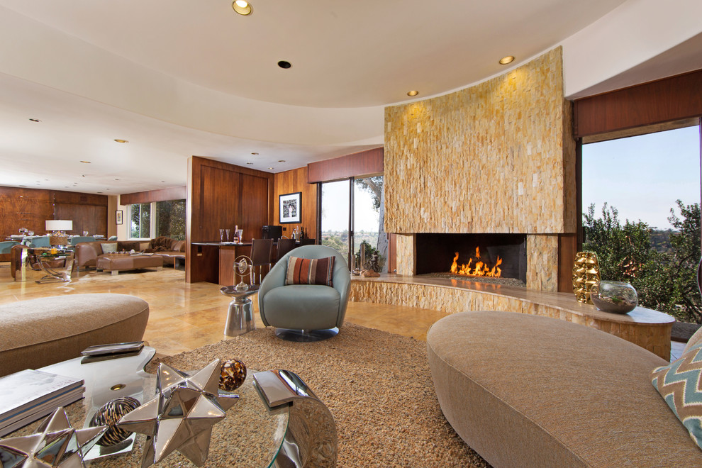 This is an example of an expansive midcentury formal open concept living room in San Diego with beige walls, travertine floors, a stone fireplace surround and a wall-mounted tv.