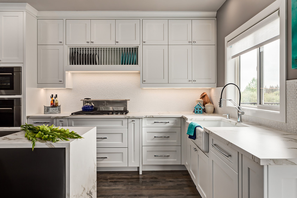 Example of a large transitional l-shaped dark wood floor open concept kitchen design in Calgary with an undermount sink, recessed-panel cabinets, white cabinets, stainless steel appliances, an island, white backsplash, ceramic backsplash and quartzite countertops