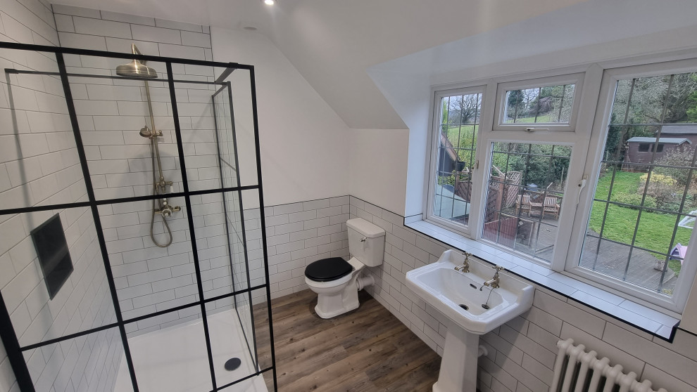 This is an example of a large traditional master bathroom in West Midlands with an open shower, a two-piece toilet, white tile, ceramic tile, white walls, vinyl floors, a pedestal sink, multi-coloured floor, an open shower, a niche and a single vanity.