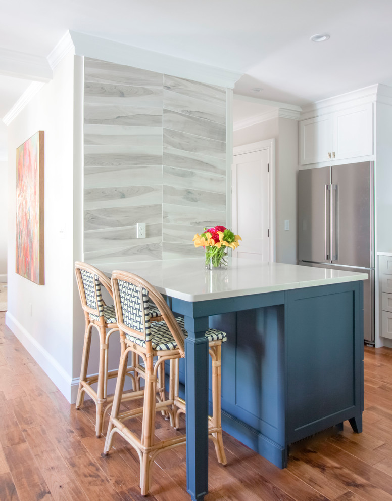 Eat-in kitchen - mid-sized transitional l-shaped light wood floor and brown floor eat-in kitchen idea in Boston with a single-bowl sink, shaker cabinets, blue cabinets, quartzite countertops, white backsplash, stone slab backsplash, stainless steel appliances, an island and white countertops
