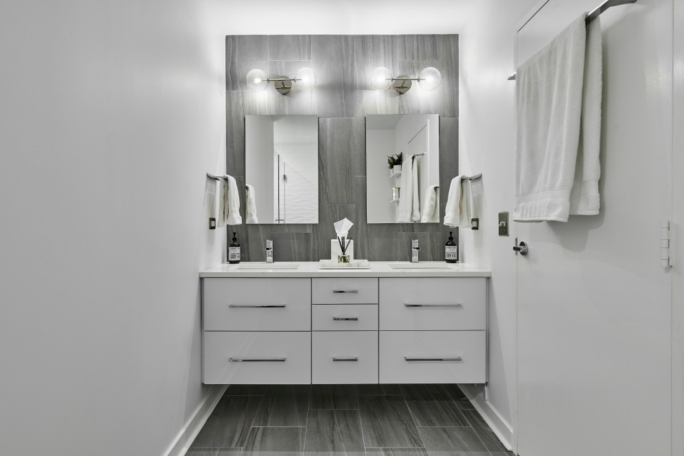 Alcove shower - large contemporary 3/4 white tile and porcelain tile porcelain tile, gray floor and double-sink alcove shower idea in Chicago with flat-panel cabinets, white cabinets, a one-piece toilet, white walls, an integrated sink, quartzite countertops, a hinged shower door, white countertops, a niche and a floating vanity