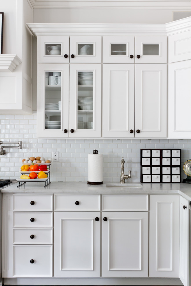 Traditional kitchen in New York with white splashback, subway tile splashback and white cabinets.