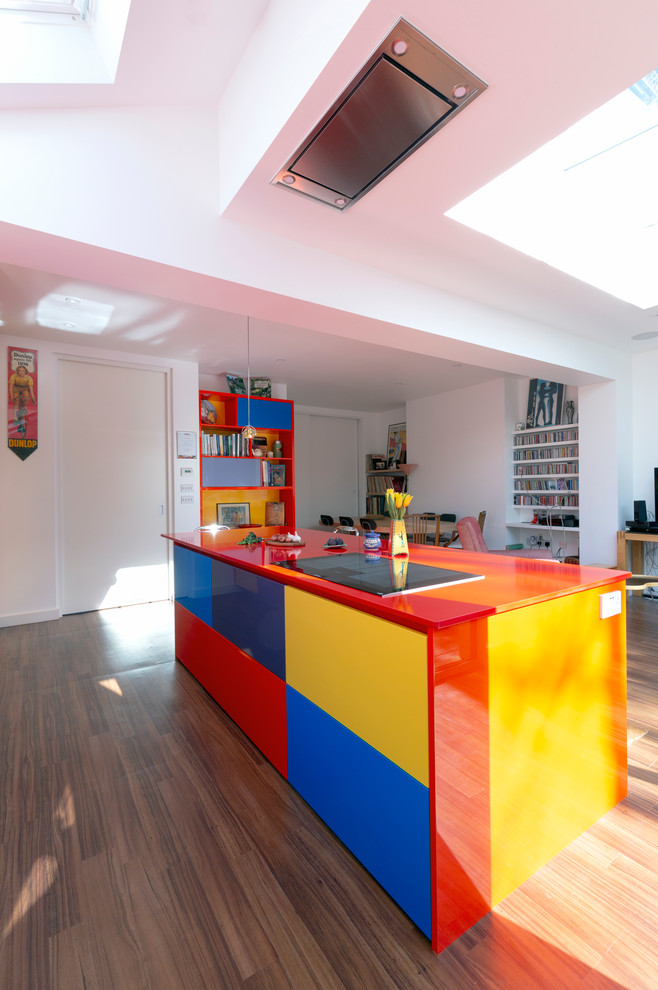 This is an example of a large contemporary kitchen in London with an integrated sink, flat-panel cabinets, laminate benchtops, stainless steel appliances, brown floor and red benchtop.
