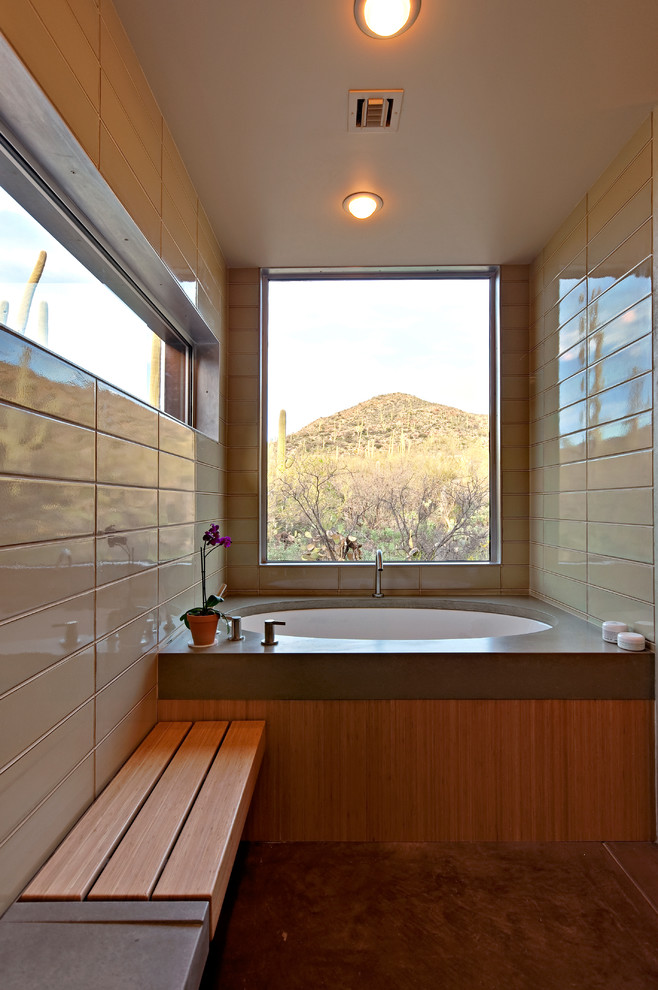 Design ideas for a large contemporary master bathroom in Phoenix with a drop-in tub, an integrated sink, flat-panel cabinets, medium wood cabinets, concrete benchtops, an open shower, a one-piece toilet, ceramic tile, beige tile, beige walls and beige floor.
