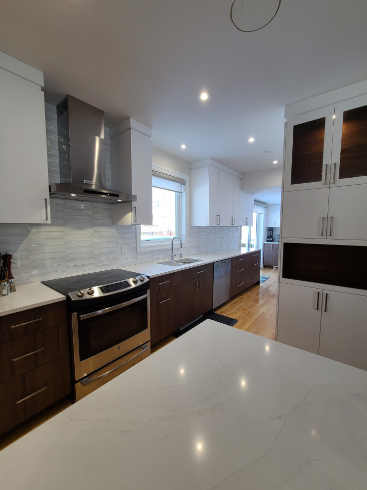 Inspiration for a medium sized modern galley open plan kitchen in Montreal with a double-bowl sink, flat-panel cabinets, white cabinets, engineered stone countertops, white splashback, porcelain splashback, stainless steel appliances, light hardwood flooring, an island, yellow floors and white worktops.