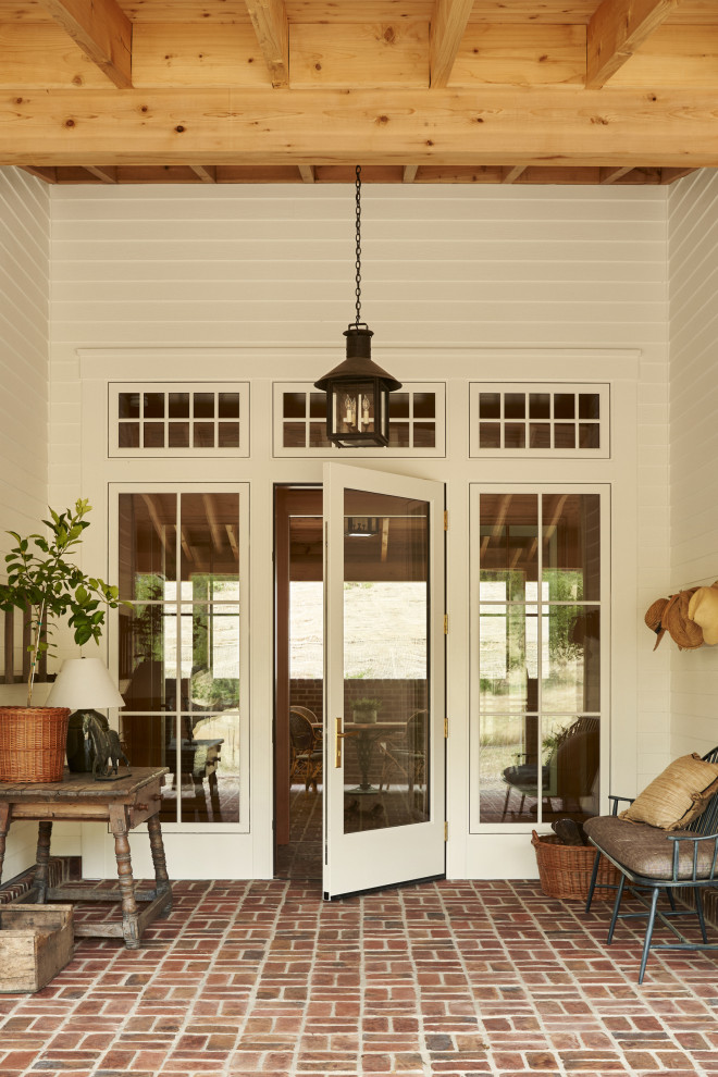 Inspiration for a country brick floor, brown floor, exposed beam and wood wall front door remodel in San Francisco with white walls and a white front door