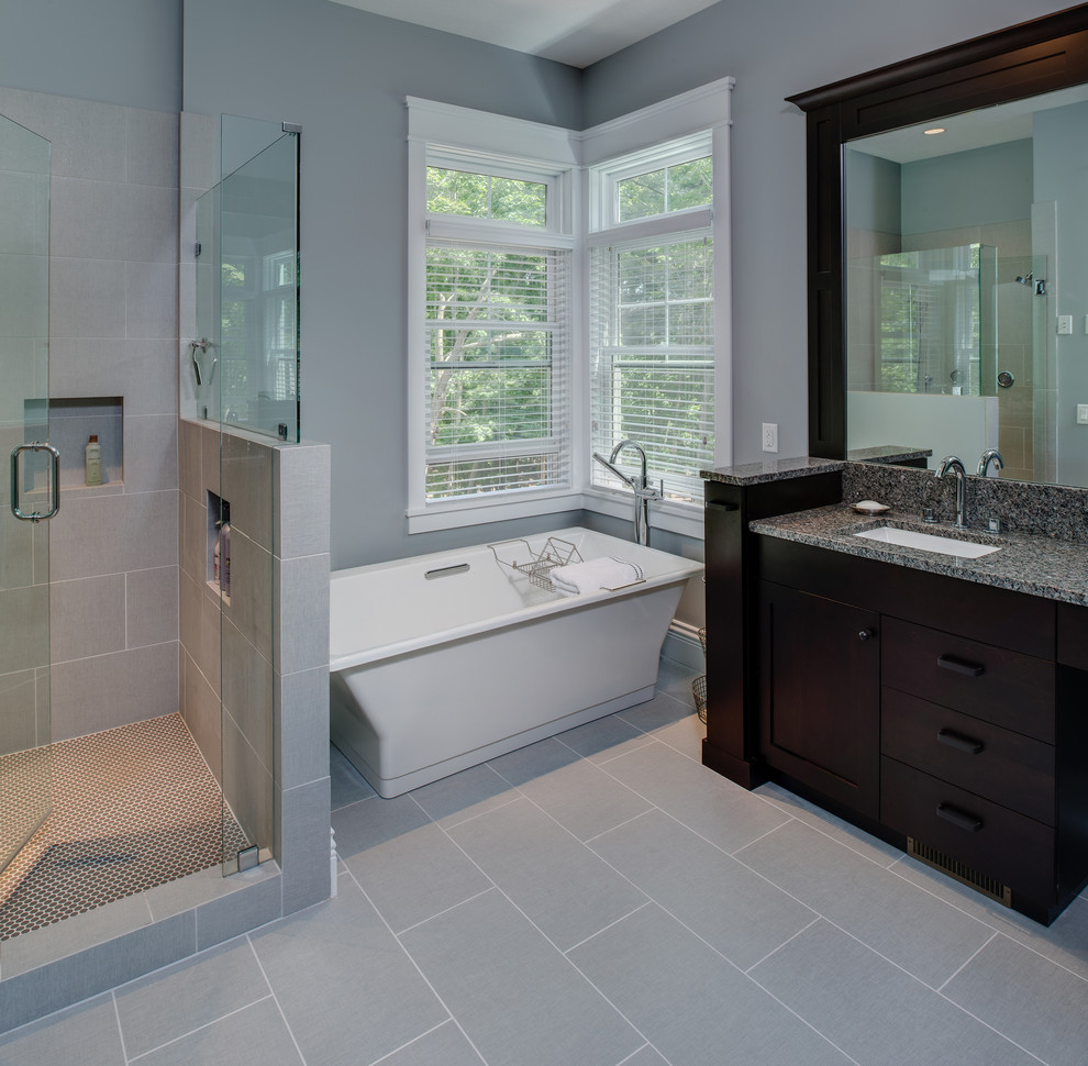Large transitional master gray tile and ceramic tile ceramic tile freestanding bathtub photo with flat-panel cabinets, gray cabinets, a two-piece toilet, gray walls, an undermount sink and granite countertops