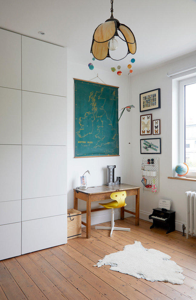 This is an example of an eclectic kids' room in London with white walls, medium hardwood floors and brown floor.